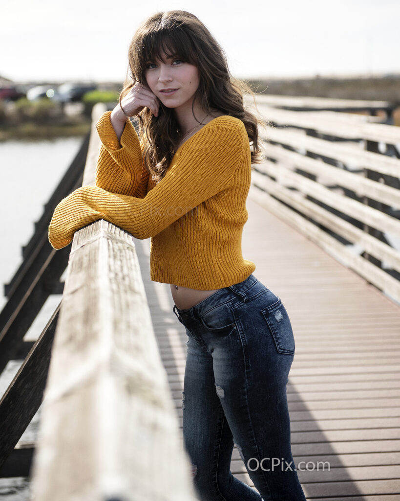 Model wearing sweater and blue jeans on bridge